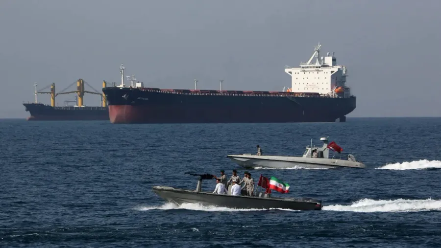 Oil tanker passing through the Strait of Hormuz with military patrol