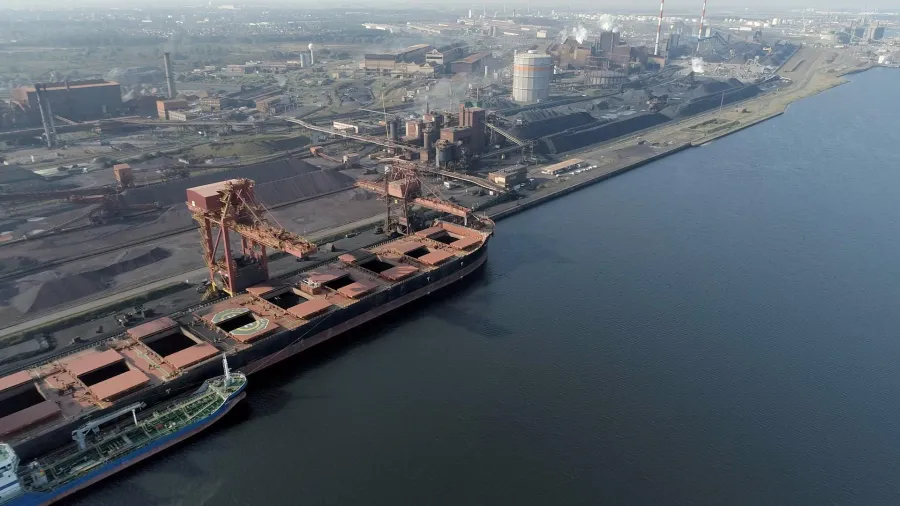 A dry-bulk carrier discharging iron ore at an industrial port