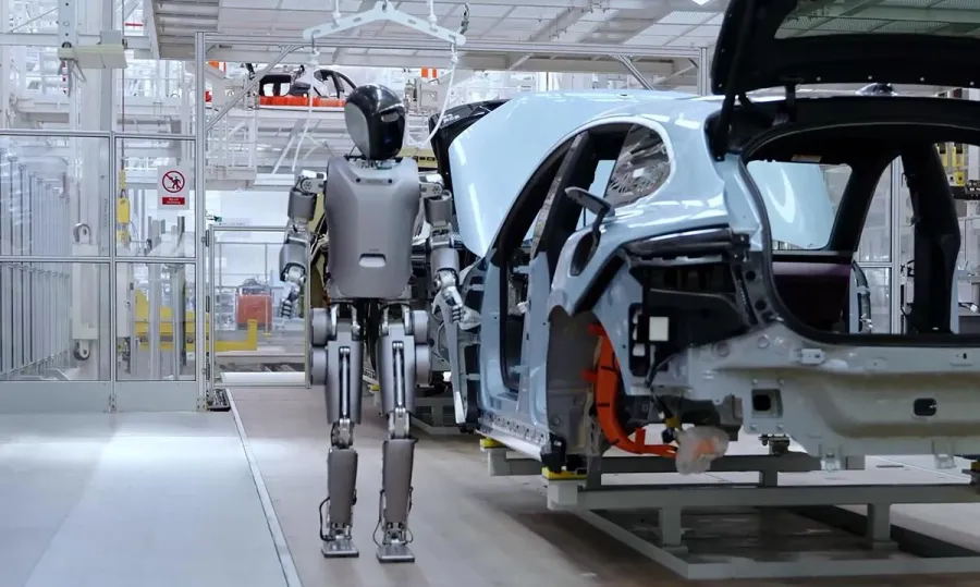 A humanoid robot standing beside an automobile assembly line in China