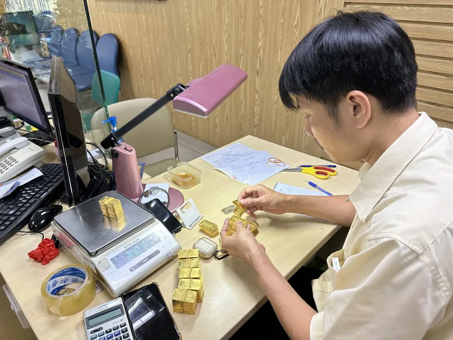 A staff member counting gold before buyback