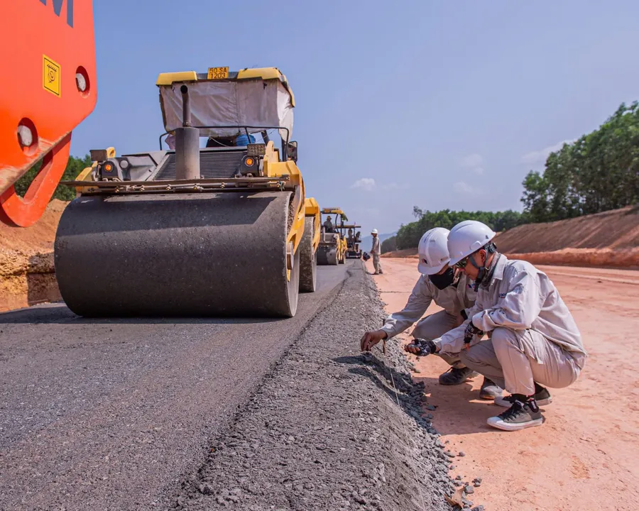 Construction site with a road roller and workers checking the road base