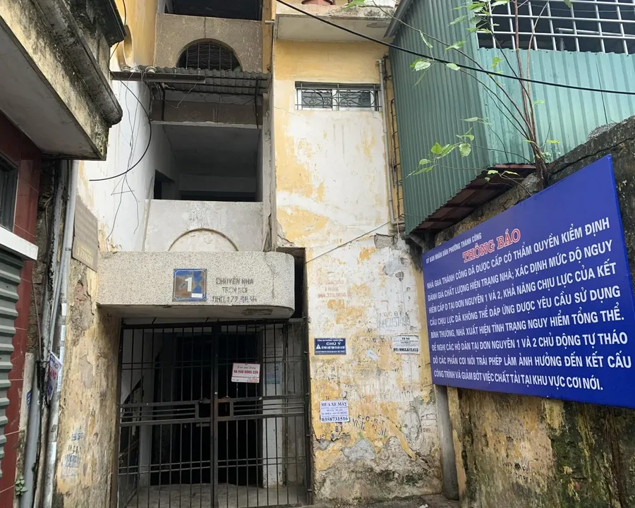 An old level-D apartment block in Hanoi with a demolition warning sign