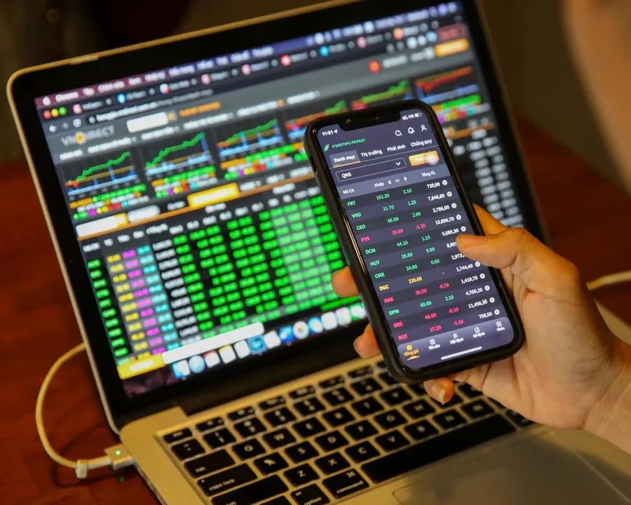 An investor watching stock prices on a laptop and a phone