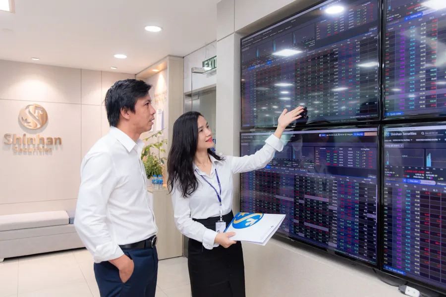 Nhà đầu tư theo dõi bảng điện chứng khoán tại công ty môi giới