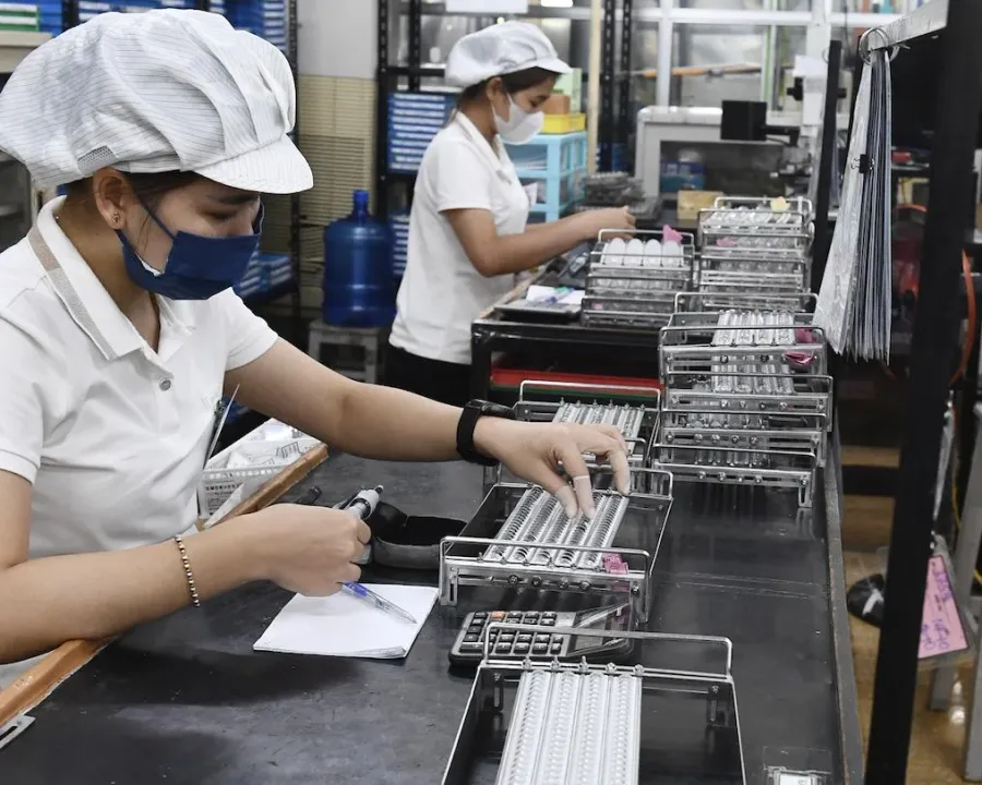 Công nhân kiểm tra linh kiện điện tử trong nhà máy