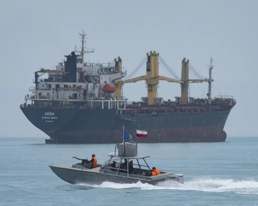Xuồng tuần tra mang cờ Vệ binh Cách mạng Iran trên eo biển Hormuz, tàu hàng phía sau là ảnh minh họa