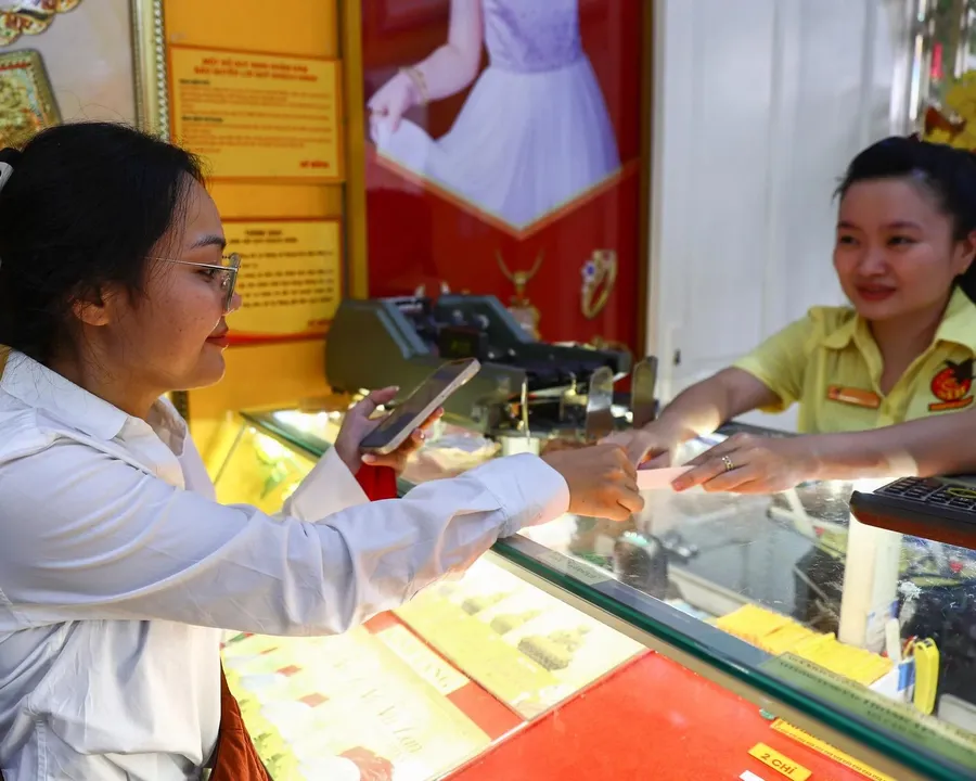 Khách dùng điện thoại thanh toán tại quầy tiệm vàng